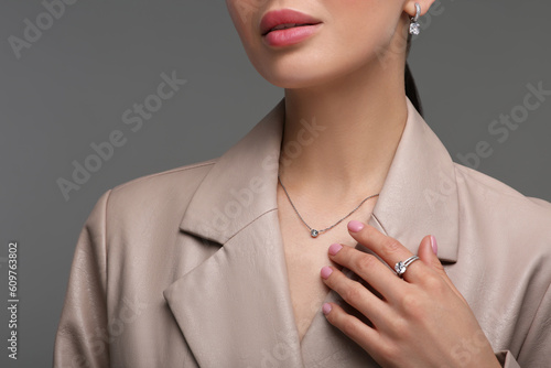 Young woman with elegant jewelry on dark grey background, closeup