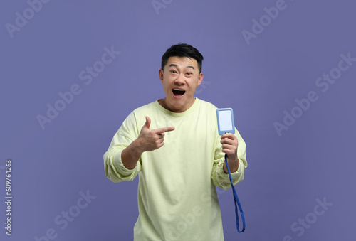 Emotional asian man with vip pass badge on purple background