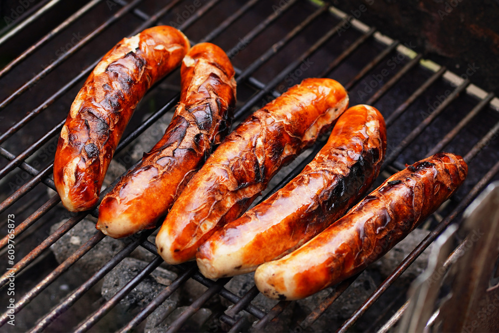 Cooking food in garden. On BBQ grill grate are fresh grilled traditional Nuremberg sausages, ready to be eaten - barbecue grilling outdoors in Germany Cooking food in garden. On BBQ grill grate are fresh grilled traditional Nuremberg sausages, ready to be eaten - barbecue grilling outdoors in Germany