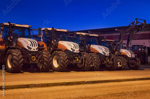Row of New Tractors Under Nighttime Illumination