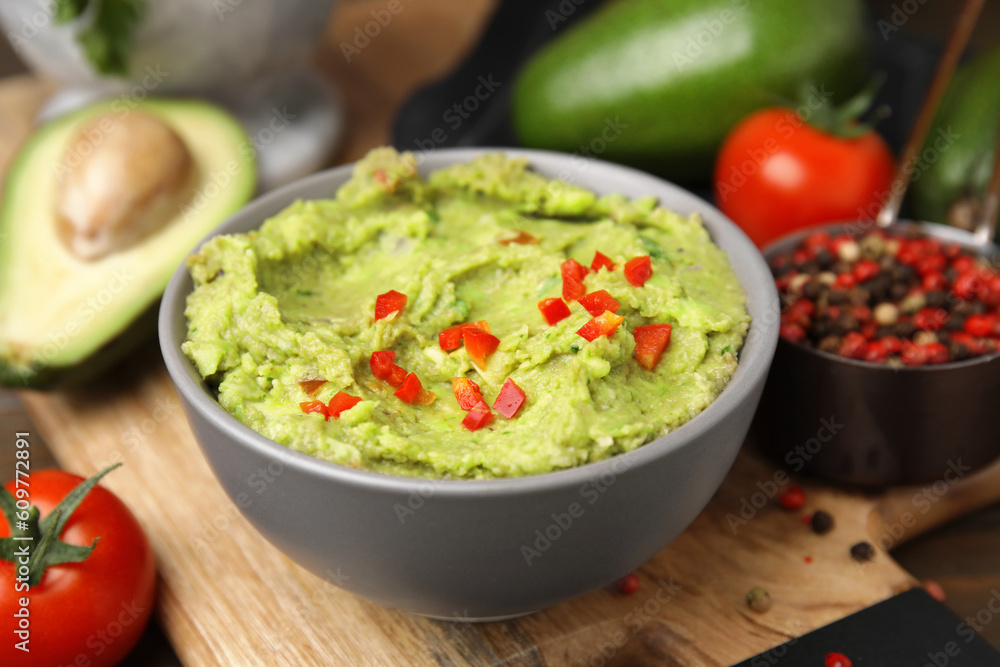 Bowl of delicious guacamole and ingredients on wooden board, closeup Bowl of delicious guacamole and ingredients on wooden board, closeup