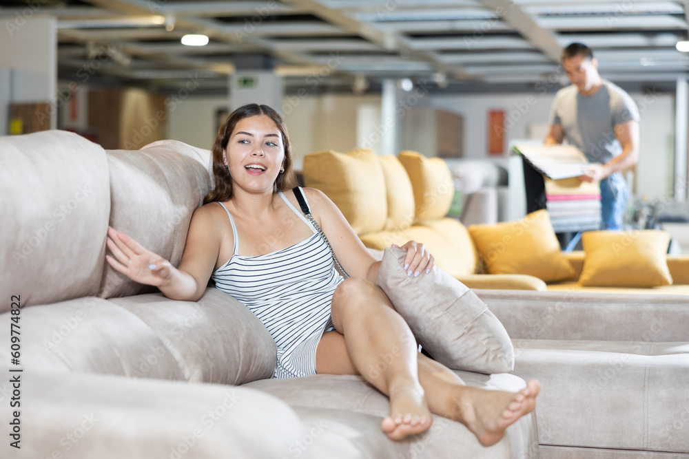 Fototapeta premium Interested woman is testing new sofa in furniture store
