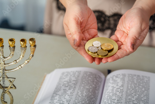Fotografia A Jewish woman reads a blessing on family wealth before the wedding, silver shekels in her hands and tegilim on the table