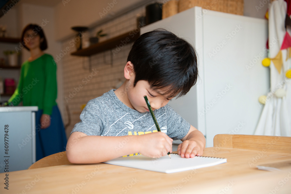 キッチンにいる母親と勉強中の男の子 キッチンにいる母親と勉強中の男の子