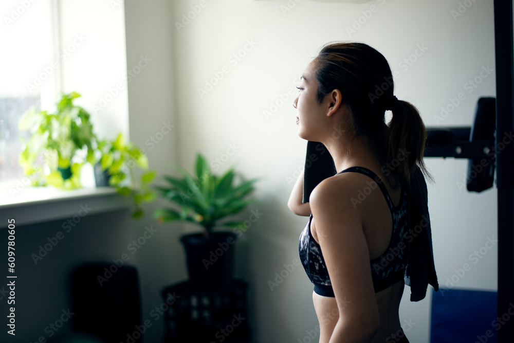 ジムで汗を拭きながら休憩をしている女性 ジムで汗を拭きながら休憩をしている女性