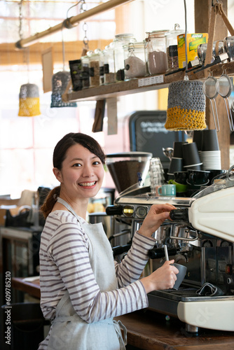 笑顔でエスプレッソマシンを触っている店員の女性 photo