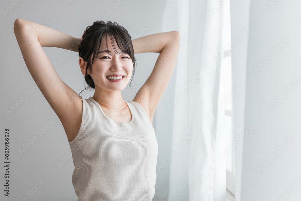 寝起き・起床時にカーテンの前でストレッチをする女性（セロトニン・リフレッシュ・柔軟体操）
