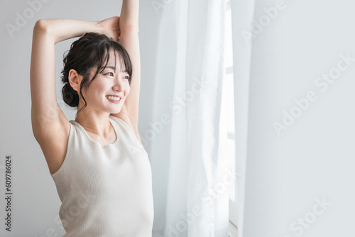 寝起き・起床時にカーテンの前でストレッチをする女性（セロトニン・リフレッシュ・柔軟体操） 