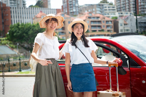 赤い車の前に立って笑っている女性2人 photo