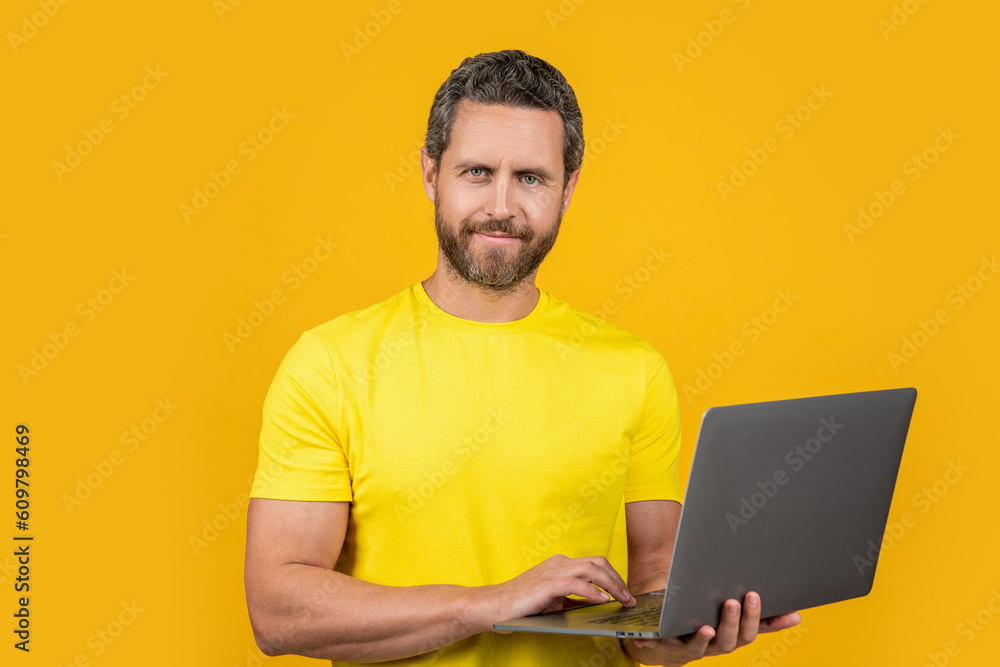 happy man blogger in studio. photo of man blogger with laptop. man blogger isolated on yellow.