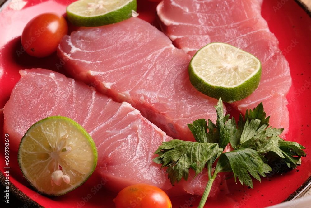 Fish filet is fish meat that has been cut or sliced away from the bone by cutting lengthwise along one side of the fish. on a brown wooden cutting board. cherry tomato, lime. Istiompax indica. Marlin
Fish filet is fish meat that has been cut or sliced away from the bone by cutting lengthwise along one side of the fish. on a brown wooden cutting board. cherry tomato, lime. Istiompax indica. Marlin