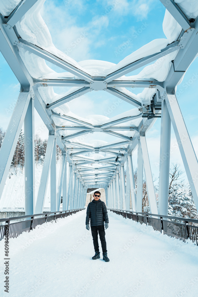 man tourist Visiting in Biei, Traveler in Sweater sightseeing Shirahige Waterfall bridge with Snow in winter. landmark and popular for attractions in Hokkaido, Japan. Travel and Vacation concept man tourist Visiting in Biei, Traveler in Sweater sightseeing Shirahige Waterfall bridge with Snow in winter. landmark and popular for attractions in Hokkaido, Japan. Travel and Vacation concept