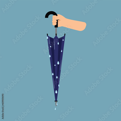 Hand holding wet blue umbrella, Folded wet umbrella, Umbrella rain protection.