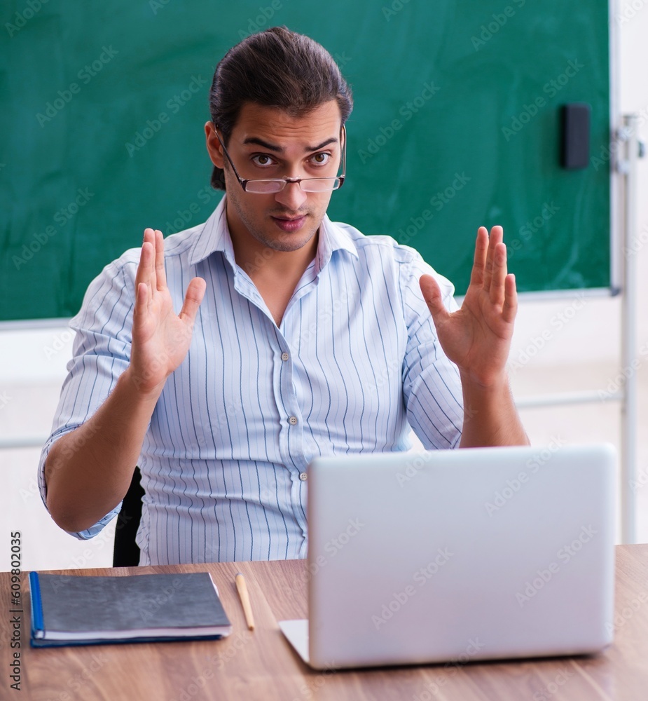 Young male teacher in front of blackboard Young male teacher in front of blackboard