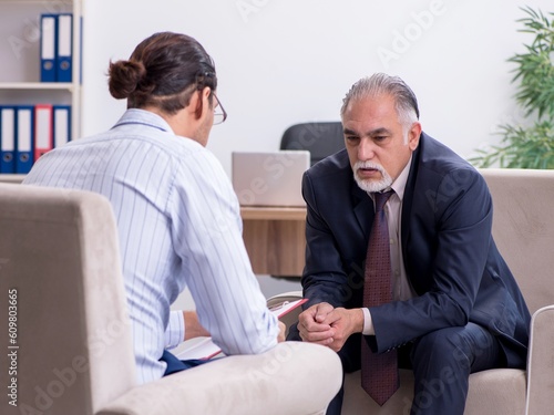 Old man visiting young male doctor psychologist