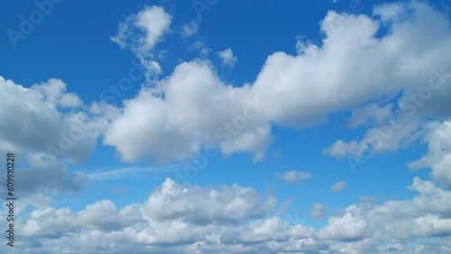 White clouds float across the blue sky. Puffy fluffy soft clouds. Timelapse.