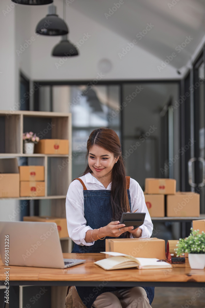 Portrait business woman smile and use tablet checking information on parcel shipping box before send to customer. Entrepreneur small business working at home. SME business online marketing. Portrait business woman smile and use tablet checking information on parcel shipping box before send to customer. Entrepreneur small business working at home. SME business online marketing.