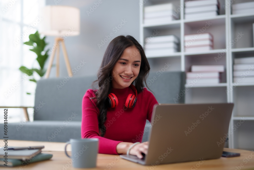 Cute Asian young woman red shirt is using laptop computer sitting on the floor in the living room, watching movie, listening to music, shopping online, watching live broadcast. Cute Asian young woman red shirt is using laptop computer sitting on the floor in the living room, watching movie, listening to music, shopping online, watching live broadcast.