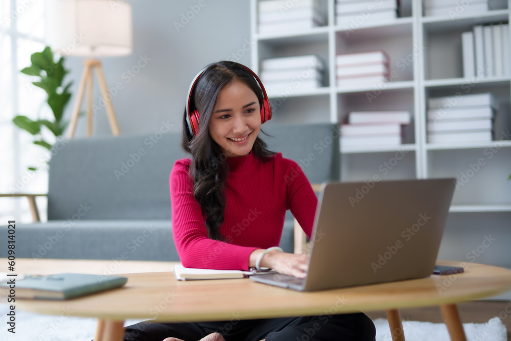 Cute Asian young woman red shirt is using laptop computer sitting on the floor in the living room, watching movie, listening to music, shopping online, watching live broadcast. Cute Asian young woman red shirt is using laptop computer sitting on the floor in the living room, watching movie, listening to music, shopping online, watching live broadcast.