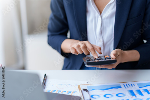 Close-up of businesswoman hands using a calculator to check company finances and earnings and budget. Business woman calculating monthly expenses, managing budget, papers, loan documents, invoices.