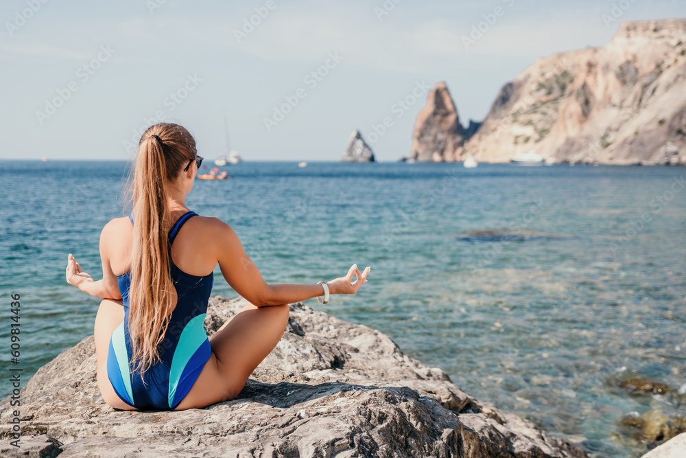 Woman sea yoga. Happy woman meditating in yoga pose on the beach, ocean and rock mountains. Motivation and inspirational fit and exercising. Healthy lifestyle outdoors in nature, fitness concept.