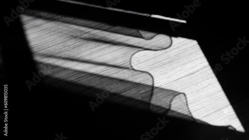 Abstract shadows of a net curtain on wooden floor as black and white photo