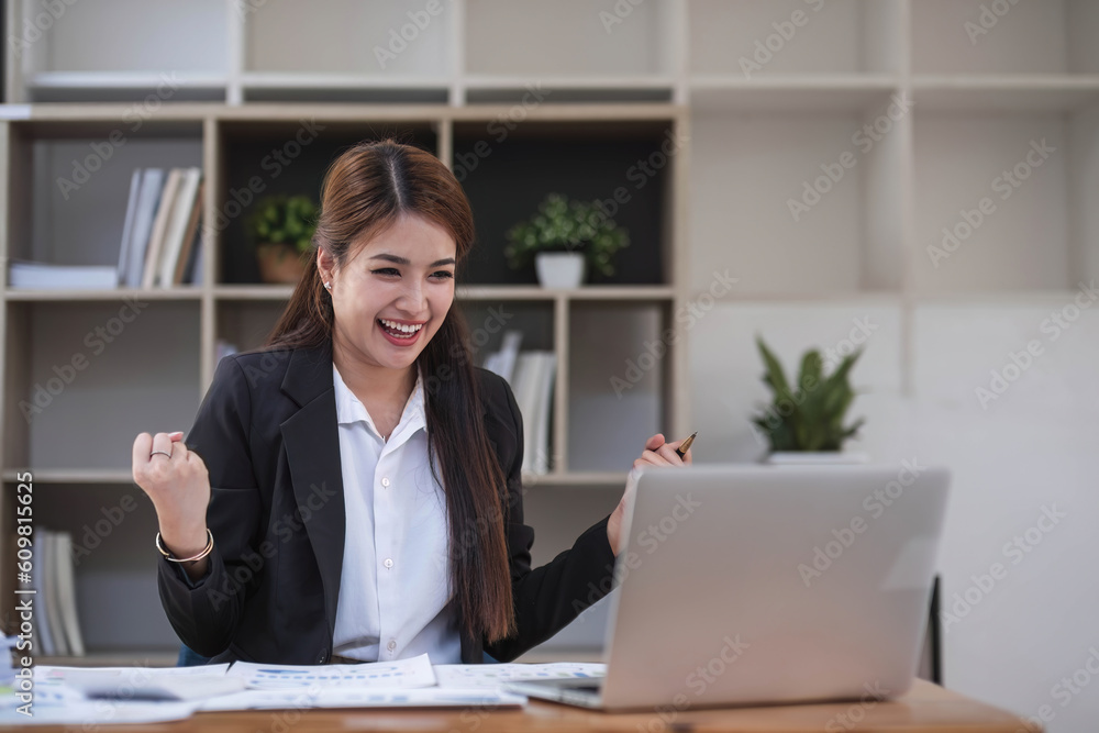 Beautiful Asian businesswoman celebrate while using laptop at office and showing delight. Startup small business and successful concept. Beautiful Asian businesswoman celebrate while using laptop at office and showing delight. Startup small business and successful concept.