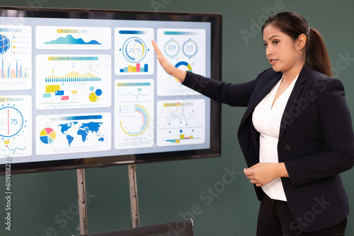 Businesswoman standing in conference room giving statistic presentation. Young Asian professional business woman talking, presenting strategy planning to executive working team in corporate meeting.