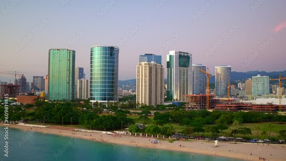 Aerial Shot Of Modern Skyscrapers Near People At Beach, Drone Flying Backward Over Sea At Sunset - Oahu, Hawaii Aerial Shot Of Modern Skyscrapers Near People At Beach, Drone Flying Backward Over Sea At Sunset - Oahu, Hawaii