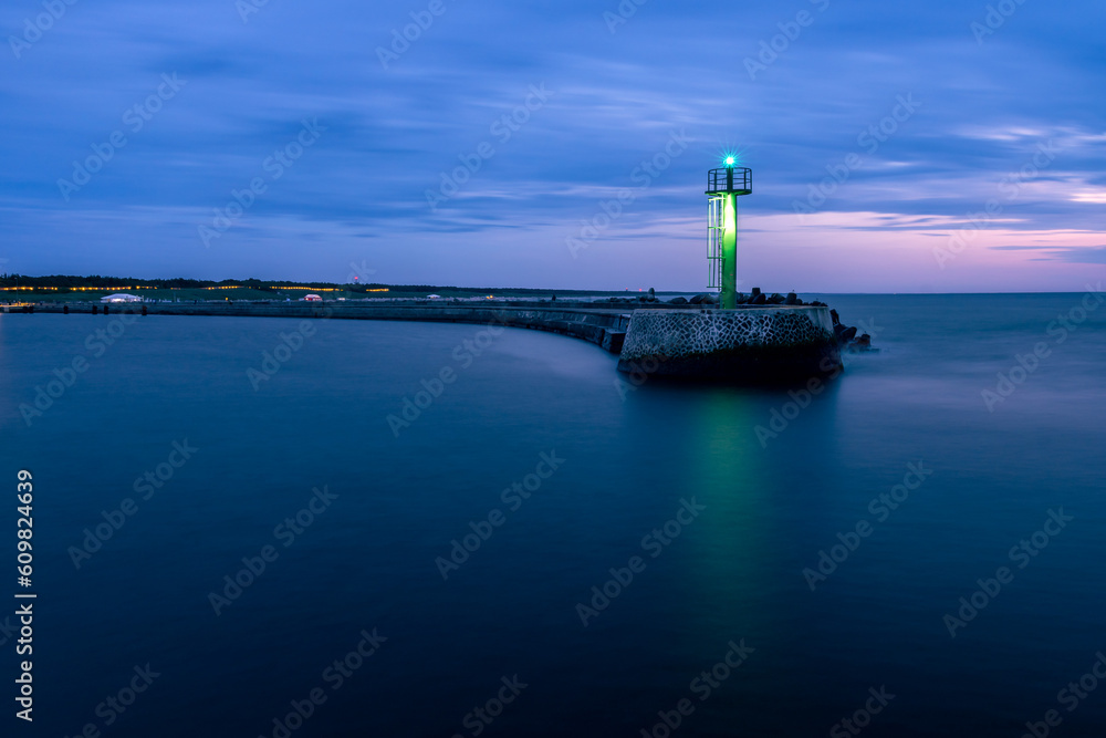 Stone pier in Darłowo in the evening. Lights on the beach. Traffic lights in the port. Blue hour. Poland