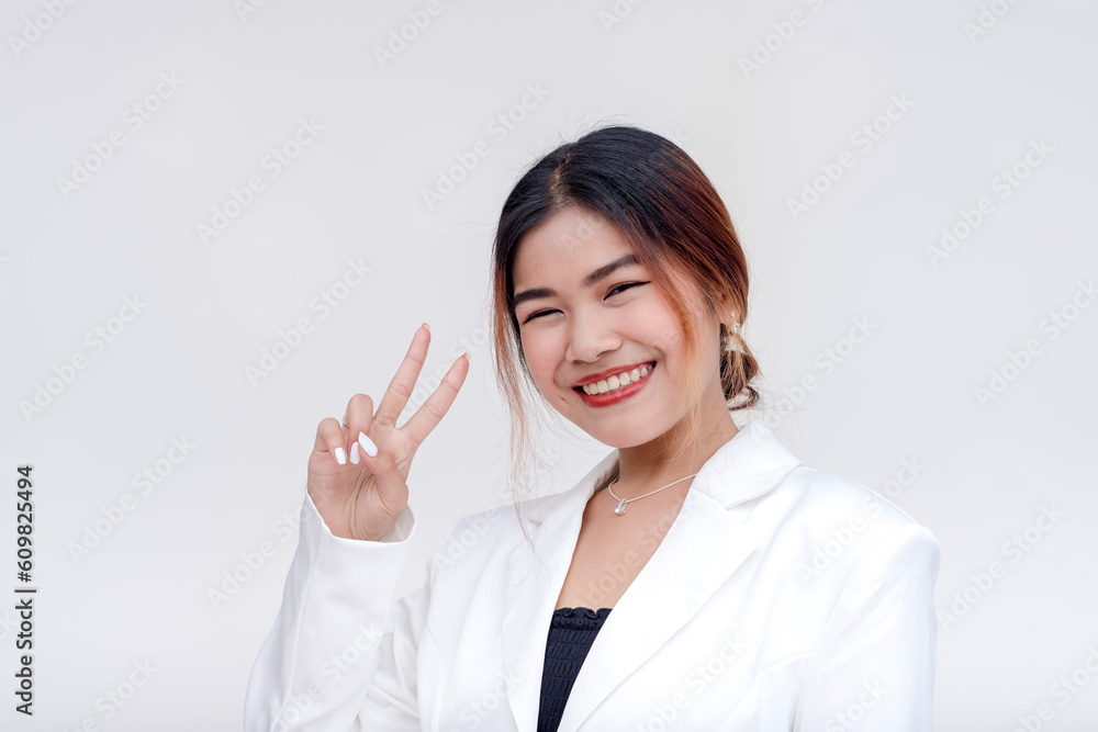 A pretty and smiling young woman posing in front of the camera while doing a peace sign. Isolated on a white background. A pretty and smiling young woman posing in front of the camera while doing a peace sign. Isolated on a white background.
