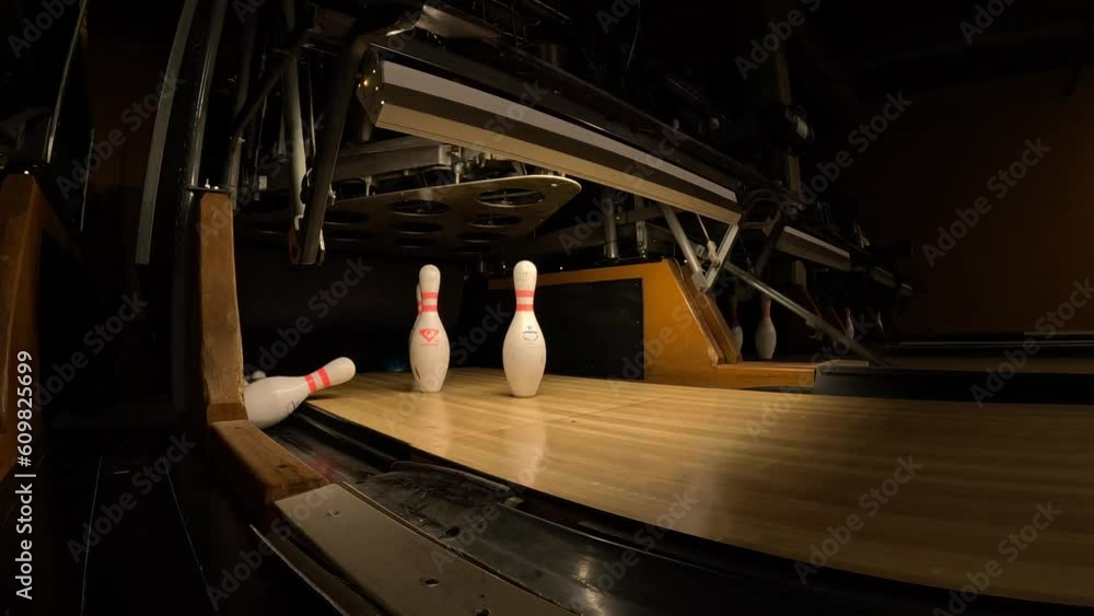 A bowling ball hits the pins behind the scenes of a bowling alley