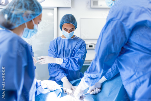 Surgery operation. Group of surgeons in operating room with surgery equipment. Medical background, selective focus. Surgeon team working together while operation