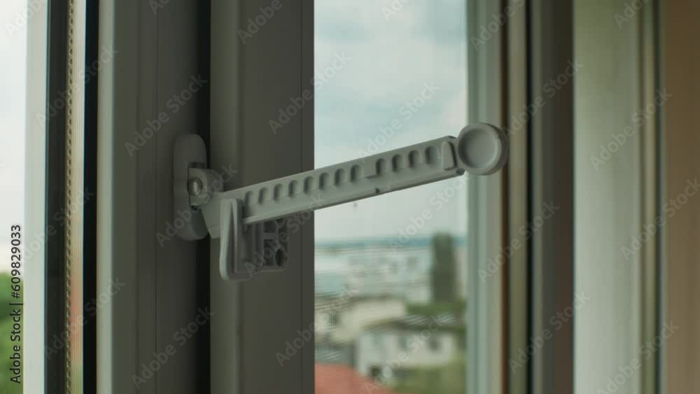 Master installed fixing limiter for opening plastic window and checks its operation. Close-up of hand in glove checking operation of window fittings. Home repairs. Installing window hardware Master installed fixing limiter for opening plastic window and checks its operation. Close-up of hand in glove checking operation of window fittings. Home repairs. Installing window hardware