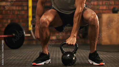Sports, kettlebell and male athlete doing a workout in the gym for strength, health and motivation. Fitness, strong and closeup of a man doing an arm exercise with weights and squats in sport center.