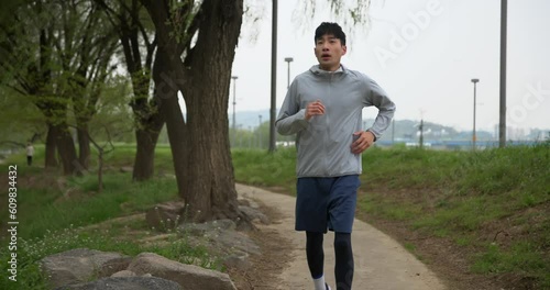 공원 숲길에서 조깅하는 젊은 남성 