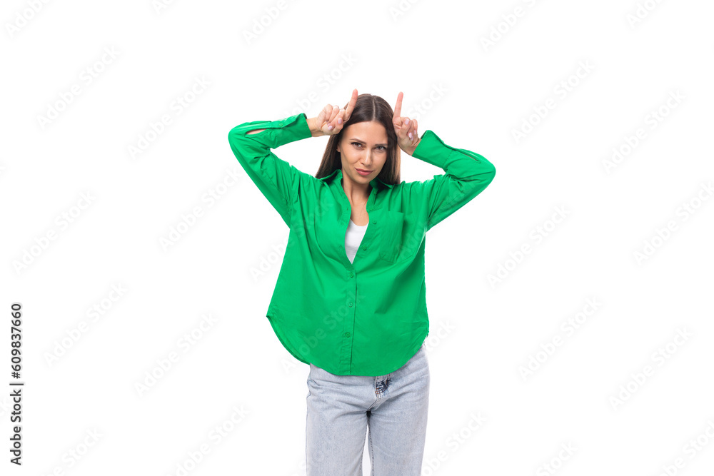 stylish slim young brunette woman with makeup in a green shirt makes a grimace on a white background with copy space stylish slim young brunette woman with makeup in a green shirt makes a grimace on a white background with copy space