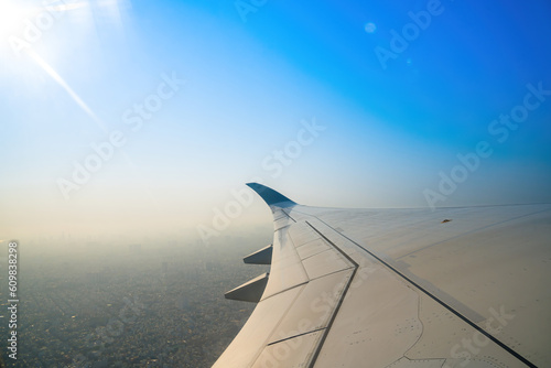 View from airplane window at airport Tan Son Nhat. Blue sky and fluffy white clouds from airplane window view, jet engine on the wing. Booking airline ticket - airplane window seat. Selective focus photo