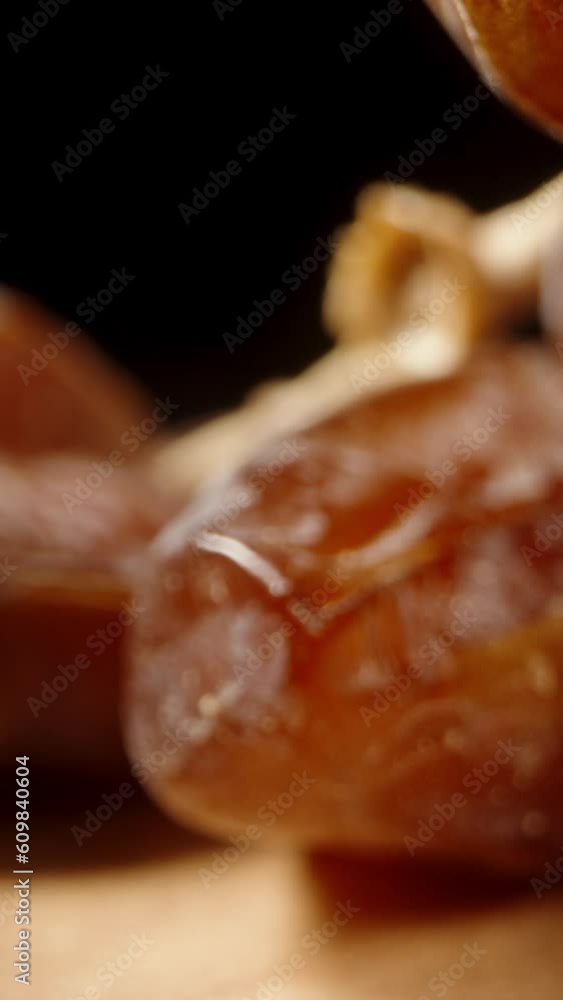 Dried dates are arranged on a wooden table, and the camera glides through them. Dolly slider extreme close-up. Vertical video. Dried dates are arranged on a wooden table, and the camera glides through them. Dolly slider extreme close-up. Vertical video.
