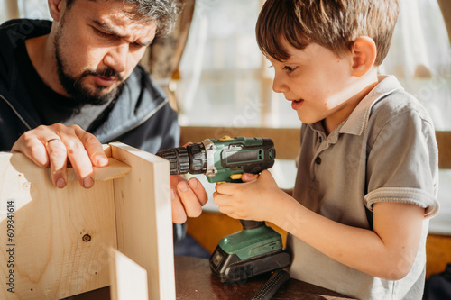 Father and son building up birdhouse at home photo