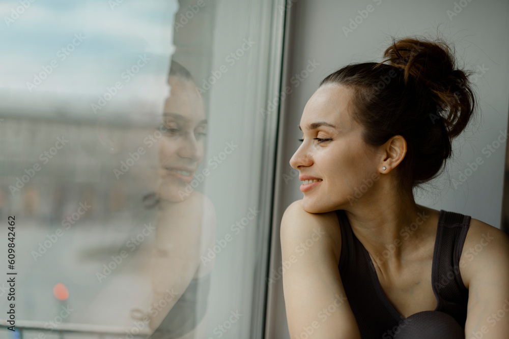 Smiling woman looking out of window at home Smiling woman looking out of window at home