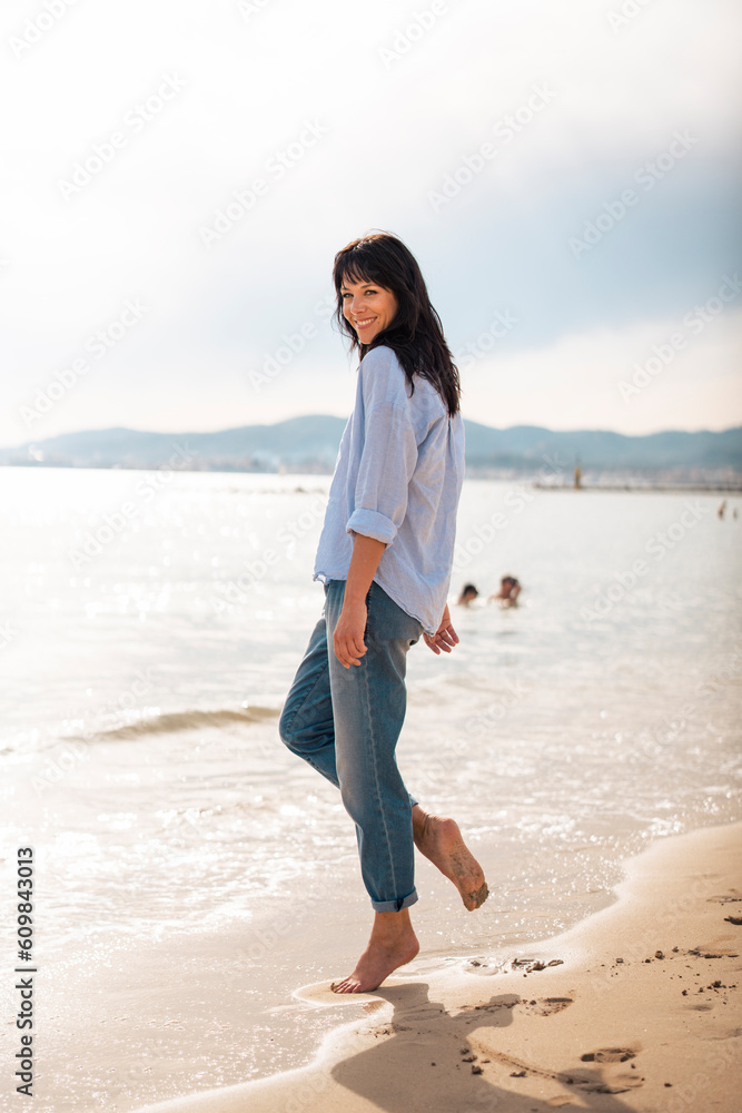 Happy mature woman standing near sea at beach Happy mature woman standing near sea at beach