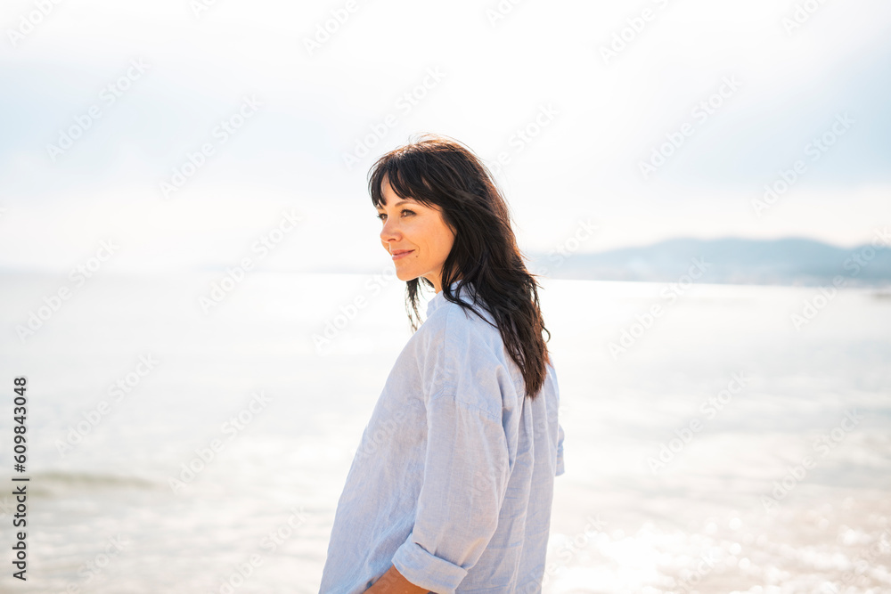 Smiling woman standing near sea at beach Smiling woman standing near sea at beach