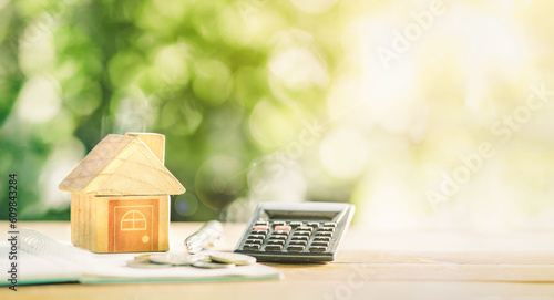 Close up house's model on notebook with calculator, coin and pen on table for Prepare planning of home loan mortgage refinance or retention interest rates, business and financial concept. investment. photo