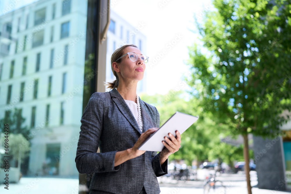 Businesswoman looking up holding tablet PC Businesswoman looking up holding tablet PC