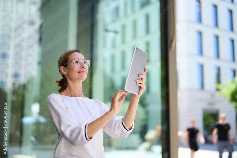 Smiling businesswoman using tablet PC near building Smiling businesswoman using tablet PC near building