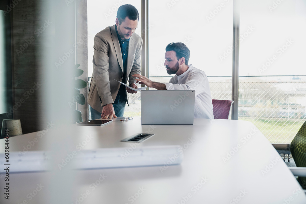 Businessman explaining document to coworker at table Businessman explaining document to coworker at table