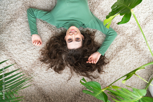 Smiling young woman lying on rug at home photo