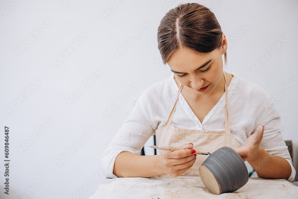 Obraz premium Woman at pottery shop decorating ceramic bowl