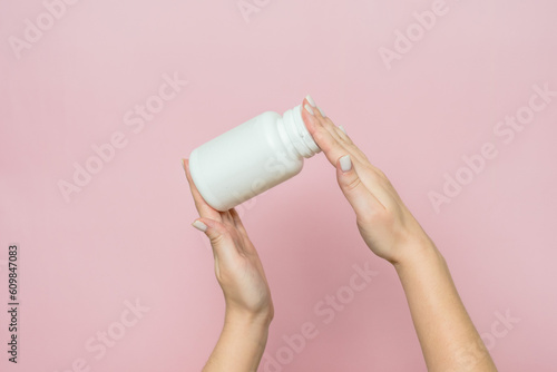 Bottle of pills or vitamins in woman's hand. Product branding mockup.